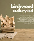 Birchwood cutlery set with wooden spoons, forks, and knives in a crate on a wooden surface.