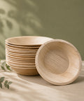 Stack of wooden bowls on a neutral background with greenery
