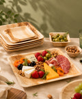Plated charcuterie board with fruits, cheese, and meats on a table with natural light.